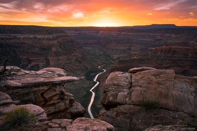 Brilliant sunset light streams under the clouds as the Dolores River streams below. Southwest Colorado.